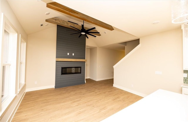 unfurnished living room with light hardwood / wood-style floors, lofted ceiling with beams, ceiling fan, and a large fireplace