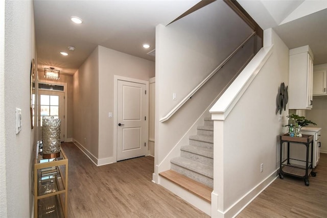 staircase featuring baseboards, wood finished floors, and recessed lighting