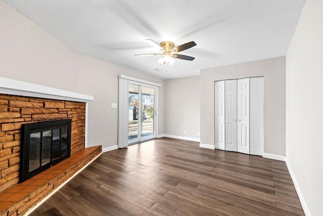 unfurnished living room featuring ceiling fan, dark hardwood / wood-style floors, and a stone fireplace