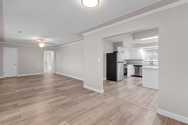 unfurnished living room with crown molding, light hardwood / wood-style flooring, sink, and ceiling fan