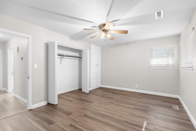 unfurnished bedroom with ceiling fan, wood-type flooring, and a closet