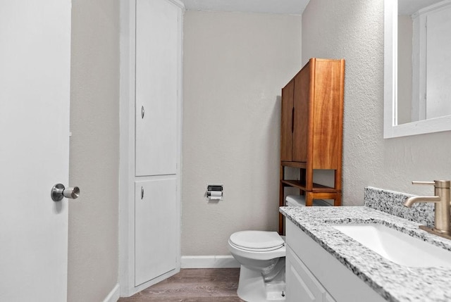 bathroom with toilet, hardwood / wood-style flooring, and vanity