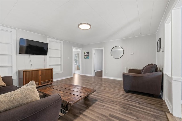 living room with built in shelves and dark wood-type flooring