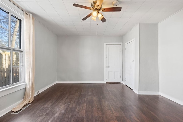 unfurnished room with a healthy amount of sunlight, ceiling fan, and dark hardwood / wood-style flooring