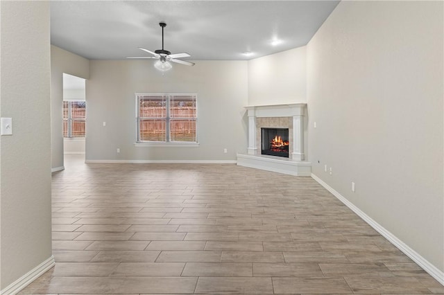 unfurnished living room featuring ceiling fan and a tiled fireplace