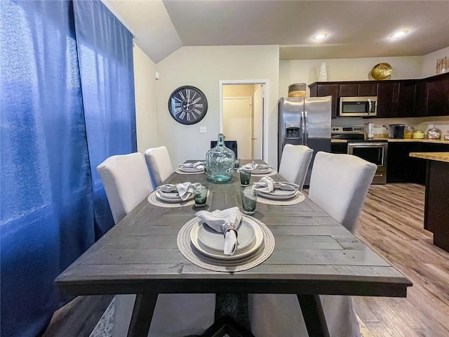 dining area with vaulted ceiling and light hardwood / wood-style floors