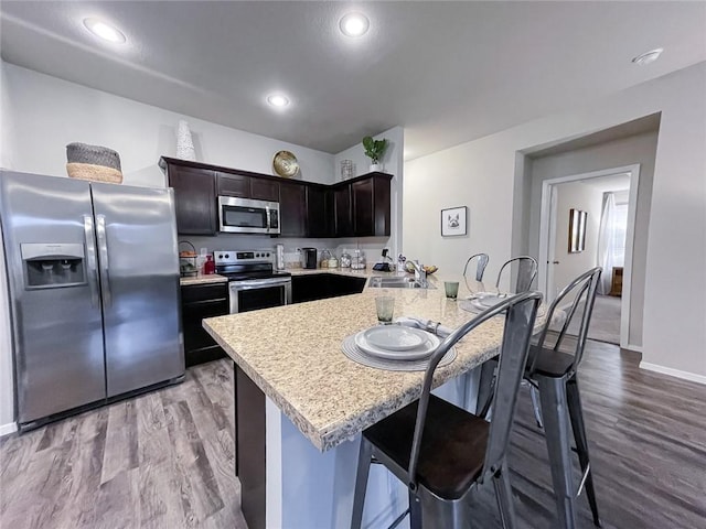 kitchen featuring a kitchen bar, stainless steel appliances, light hardwood / wood-style floors, sink, and dark brown cabinets