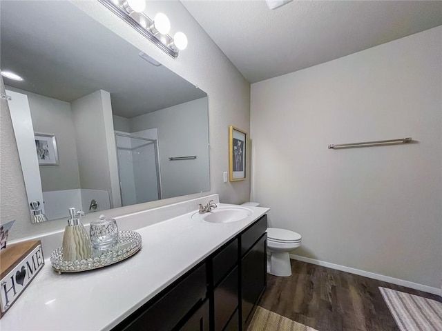 bathroom with hardwood / wood-style flooring, an enclosed shower, vanity, and toilet