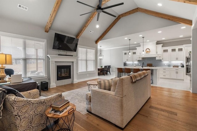 living room with ceiling fan, beamed ceiling, and light hardwood / wood-style floors