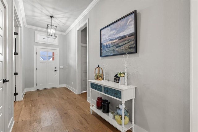 foyer with hardwood / wood-style floors, ornamental molding, and a notable chandelier