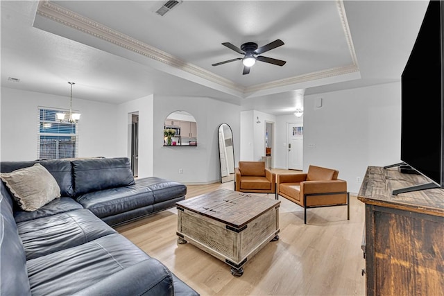 living room featuring ceiling fan with notable chandelier, crown molding, light hardwood / wood-style flooring, and a raised ceiling