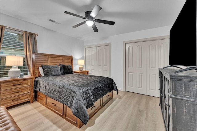 bedroom featuring ceiling fan, two closets, and light wood-type flooring