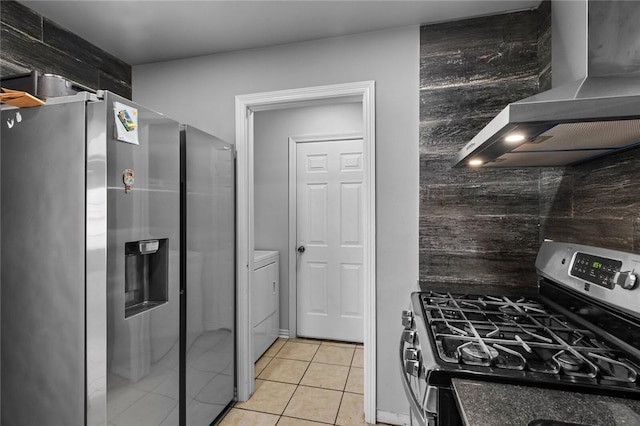 kitchen featuring stainless steel appliances, washer / clothes dryer, light tile patterned floors, and wall chimney range hood