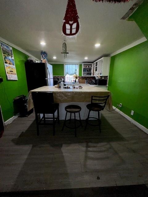 kitchen with stainless steel refrigerator, a kitchen breakfast bar, kitchen peninsula, and white cabinets