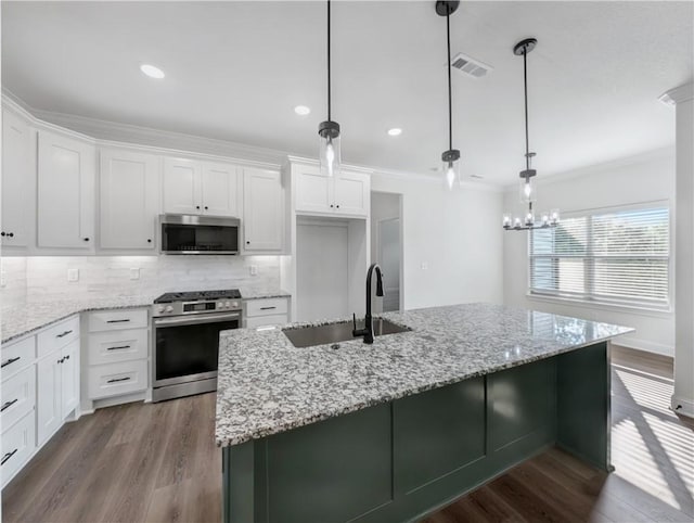 kitchen featuring sink, a kitchen island with sink, hanging light fixtures, stainless steel appliances, and white cabinets