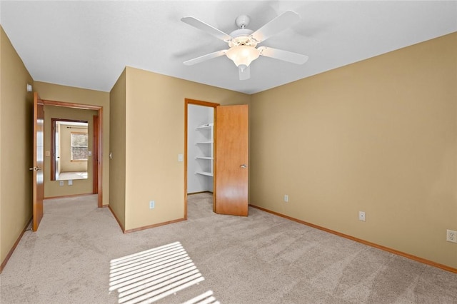 unfurnished bedroom with ceiling fan, light colored carpet, a closet, and a walk in closet