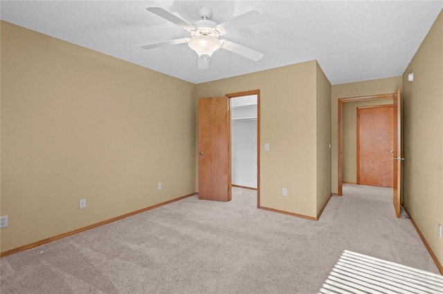 unfurnished bedroom featuring ceiling fan, light colored carpet, and a walk in closet