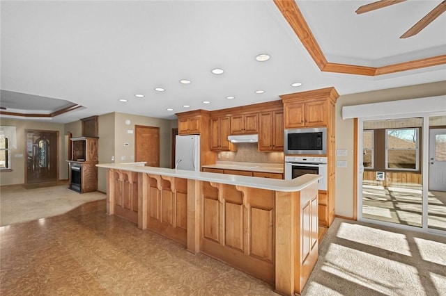 kitchen featuring built in microwave, white refrigerator, a raised ceiling, a large island, and oven