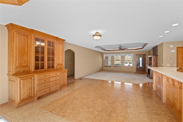 unfurnished living room featuring a tray ceiling and ceiling fan