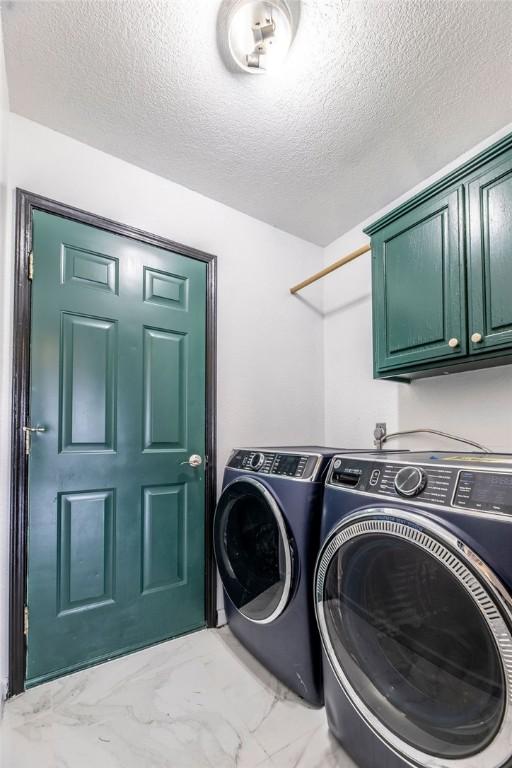 washroom featuring washer and clothes dryer, cabinets, and a textured ceiling