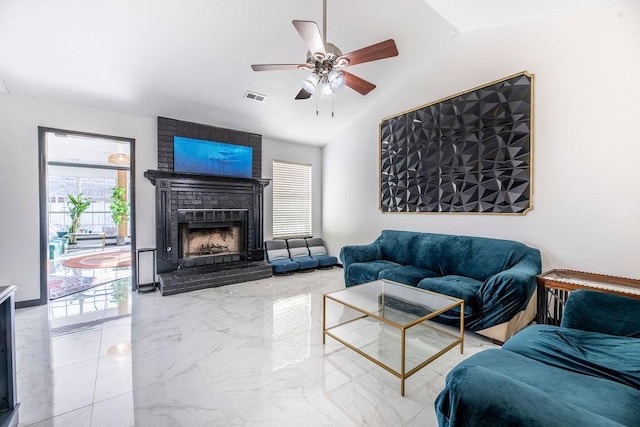 living room with ceiling fan, plenty of natural light, vaulted ceiling, and a brick fireplace