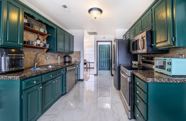 kitchen featuring sink, green cabinets, dark stone countertops, stainless steel appliances, and tasteful backsplash