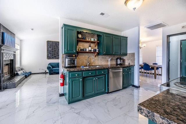 kitchen featuring sink, tasteful backsplash, stainless steel dishwasher, green cabinets, and a fireplace