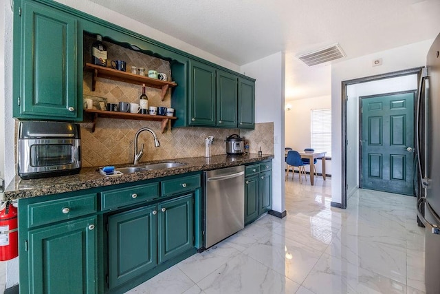 kitchen with stainless steel appliances, sink, green cabinets, and backsplash