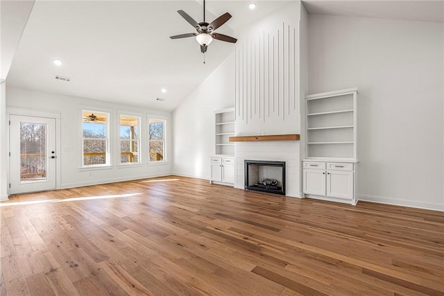 unfurnished living room featuring visible vents, a large fireplace, a healthy amount of sunlight, and light wood-style flooring