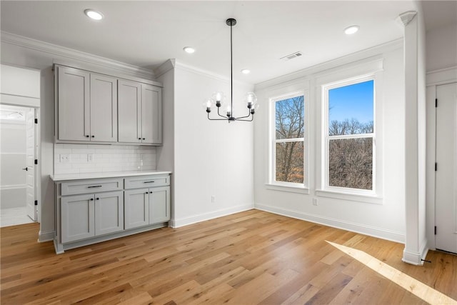 unfurnished dining area featuring baseboards, a chandelier, light wood-type flooring, ornamental molding, and recessed lighting