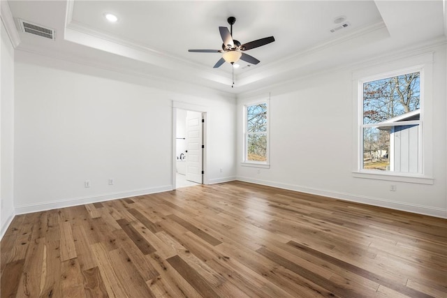 spare room with visible vents, wood finished floors, a raised ceiling, and ornamental molding