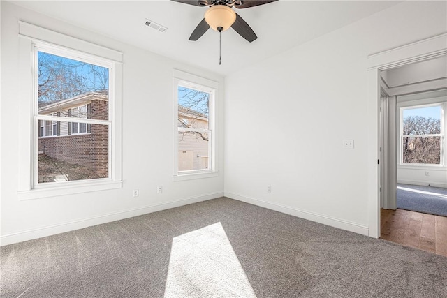 empty room with visible vents, ceiling fan, baseboards, and carpet