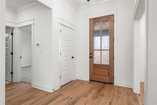 foyer entrance with light wood-style floors, baseboards, and ornamental molding