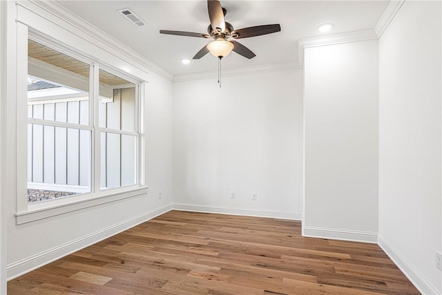 spare room featuring crown molding, wood finished floors, visible vents, and baseboards