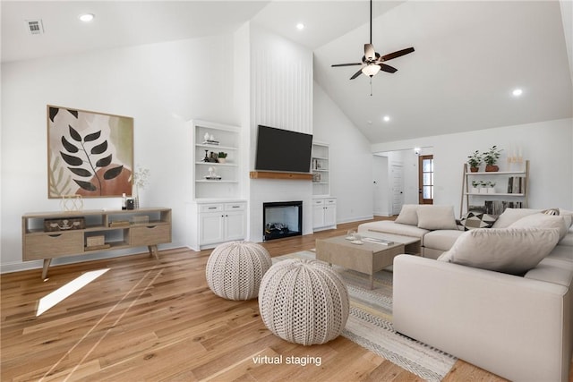 living area featuring visible vents, high vaulted ceiling, light wood-style flooring, a ceiling fan, and a fireplace