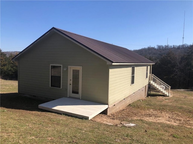 back of property with crawl space, metal roof, a lawn, and a wooden deck