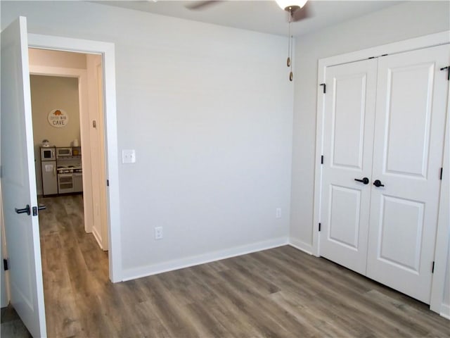 unfurnished bedroom with ceiling fan, dark hardwood / wood-style floors, and a closet