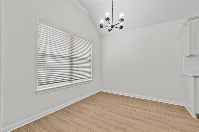 unfurnished dining area featuring an inviting chandelier, light hardwood / wood-style floors, and vaulted ceiling