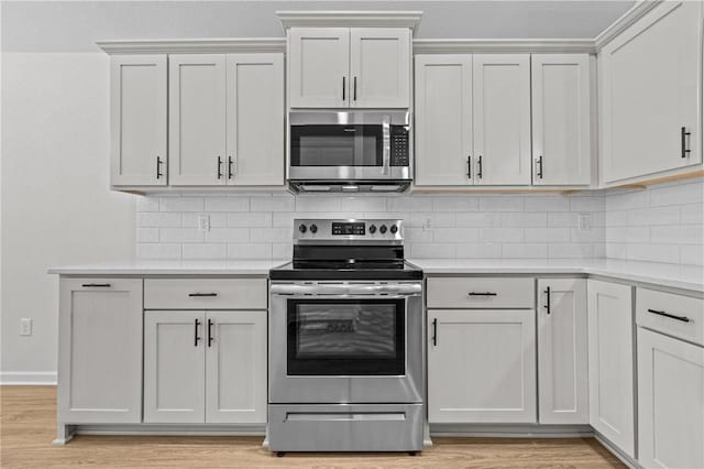 kitchen with white cabinetry, appliances with stainless steel finishes, backsplash, and light wood-type flooring