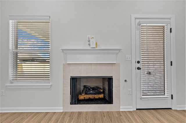 living room with wood-type flooring, a tiled fireplace, and a wealth of natural light