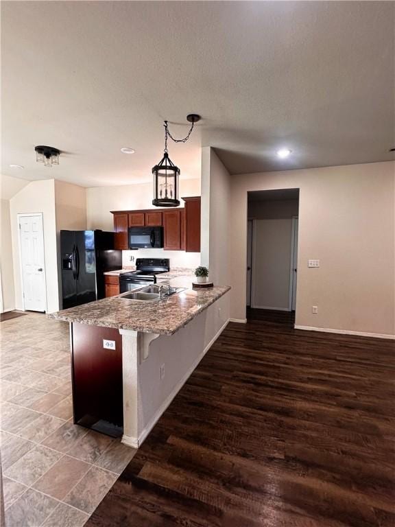 kitchen with black appliances, a kitchen breakfast bar, hanging light fixtures, kitchen peninsula, and light stone countertops