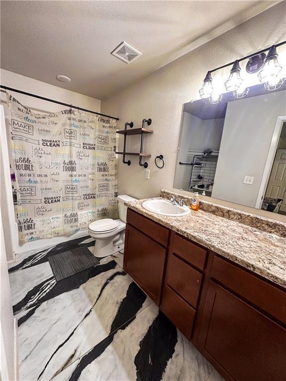 bathroom with vanity, toilet, a textured ceiling, and walk in shower