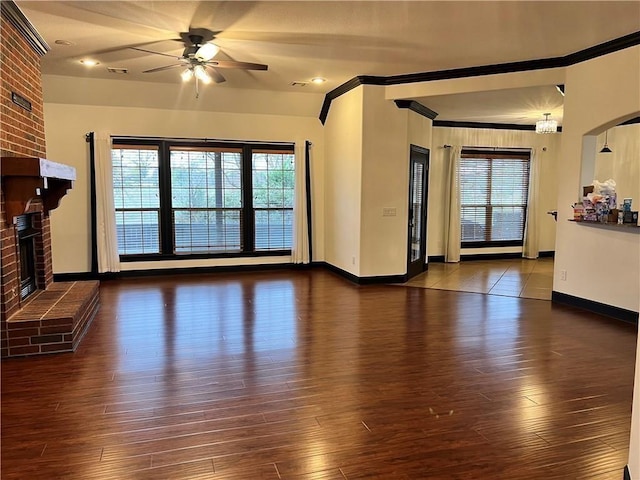 unfurnished living room with ornamental molding, dark wood-type flooring, ceiling fan, and a fireplace