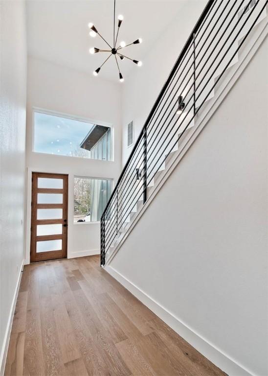 entryway with a notable chandelier, a high ceiling, and light wood-type flooring