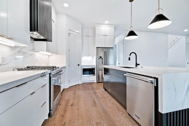 kitchen with white cabinetry, tasteful backsplash, hanging light fixtures, light wood-type flooring, and appliances with stainless steel finishes