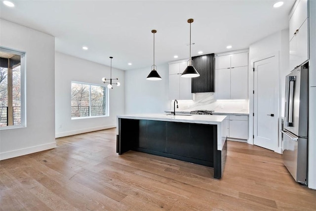 kitchen featuring white cabinetry, pendant lighting, a kitchen island with sink, and high end refrigerator