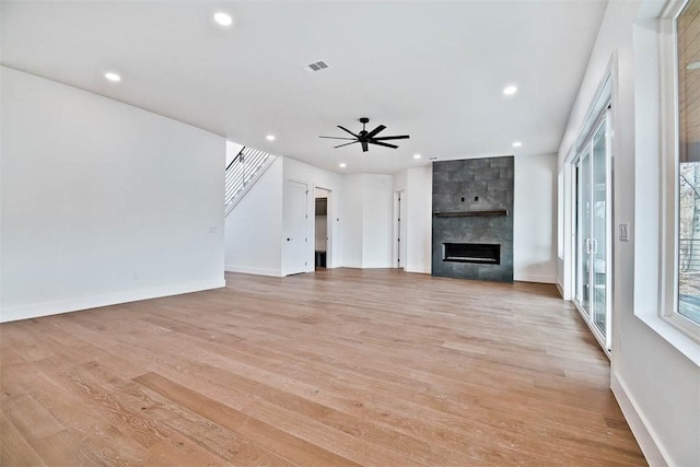 unfurnished living room featuring ceiling fan, a fireplace, and light hardwood / wood-style flooring