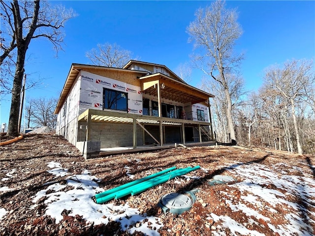 snow covered back of property featuring a balcony