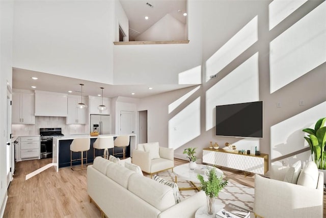 living room with a towering ceiling and light hardwood / wood-style flooring