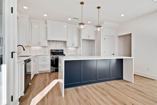 kitchen with premium range hood, stainless steel gas range oven, white cabinetry, a kitchen island, and pendant lighting